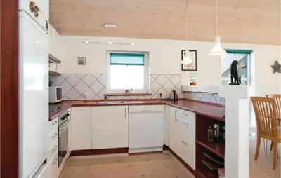 a kitchen with white cabinets and a wooden ceiling at Three-Bedroom Holiday Home In Blokhus in Blokhus