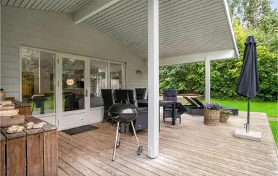 a covered patio with a grill and a table and chairs at Four-Bedroom Holiday Home In Spottrup in Spottrup