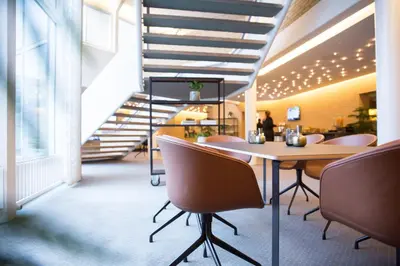 a room with a table and chairs and a staircase at Comwell Rebild Bakker in Skorping