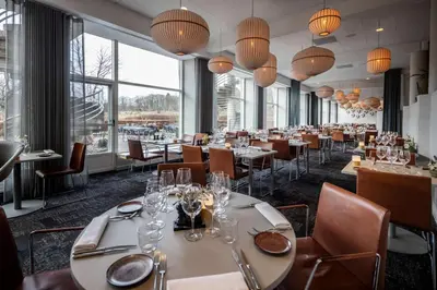 a restaurant with tables and chairs and large windows at Comwell Rebild Bakker in Skorping