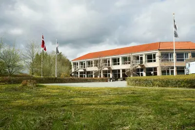 a building with two flags in front of it at Comwell Rebild Bakker in Skorping