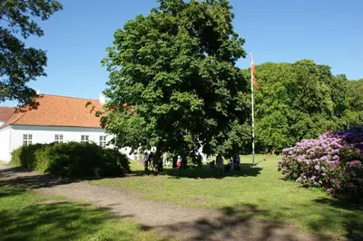 a house with a flag in a yard with flowers at Store Restrup Manor House in Store Restrup