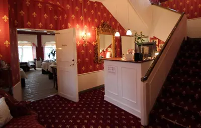 a dining room with a staircase and red walls at Store Restrup Manor House in Store Restrup