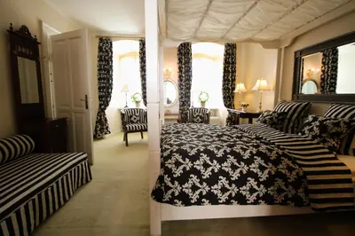 a bedroom with a bed and two chairs in it at Kokkedal Slotshotel in Brovst