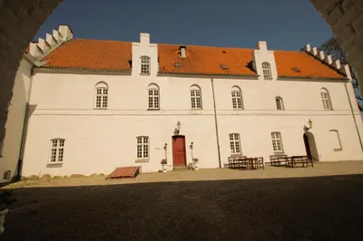 a large white building with a red roof at Kokkedal Slotshotel in Brovst
