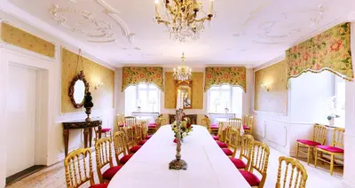 a dining room with a long table and chairs at Kokkedal Slotshotel in Brovst