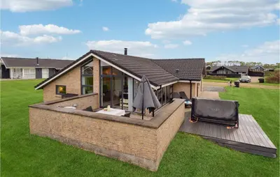a house with a deck with a chair on it at Three-Bedroom Holiday Home In Vinderup in Vinderup