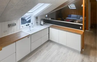a kitchen with white cabinets and a sink and a couch at Three-Bedroom Holiday Home In Thyholm in Thyholm