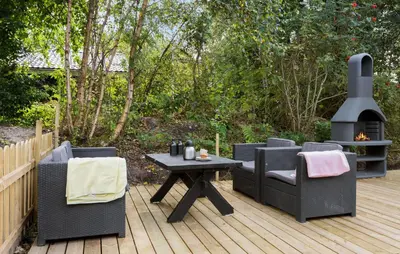 a patio with a grill and chairs and a table at Three-Bedroom Holiday Home In Thyholm in Thyholm