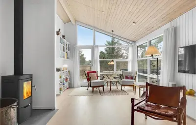 a living room with a fireplace and a table and chairs at Four-Bedroom Holiday Home In Fjerritslev in Fjerritslev