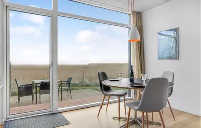 a dining room with a table and chairs and a large window at One-Bedroom Holiday Home In Ulfborg in Ulfborg