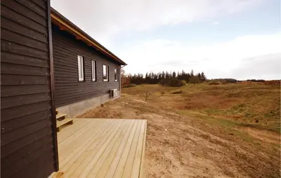a building with a wooden deck next to a field at Three-Bedroom Holiday Home In Skals in Skals