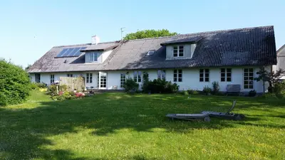 a white house with solar panels on top of a yard at Slettegaard in Slettestrand