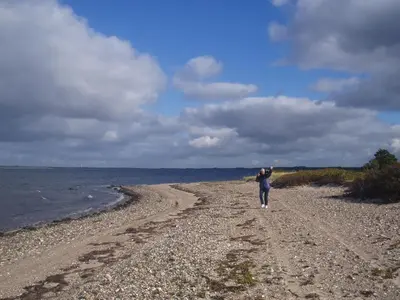 a person walking on a beach near the water at Country house in Karby