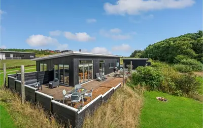 a house in a field with a deck at Three-Bedroom Holiday Home In Spottrup in Spottrup