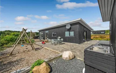 a small black house with a garden and a patio at Three-Bedroom Holiday Home In Spottrup in Spottrup