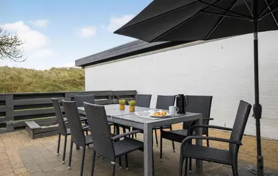 a table with chairs and an umbrella on a patio at Three-Bedroom Holiday Home In Pandrup in Pandrup
