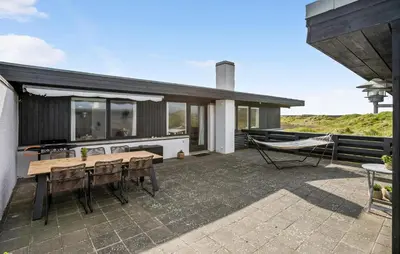 a house with a patio with a table and a hammock at Two-Bedroom Holiday Home In Pandrup in Pandrup