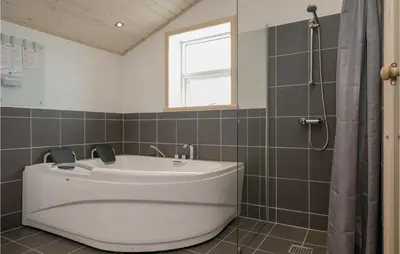 a white tub in a bathroom with a window at Four-Bedroom Holiday Home In Lokken in Løkken