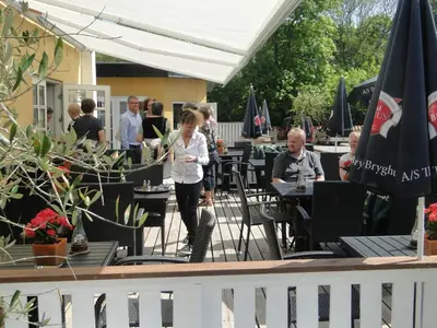a group of people sitting at tables in a restaurant at Thinghuskroen in Vestervig