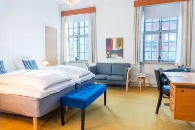 a bedroom with a bed and a couch and a desk at Palads Hotel in Viborg