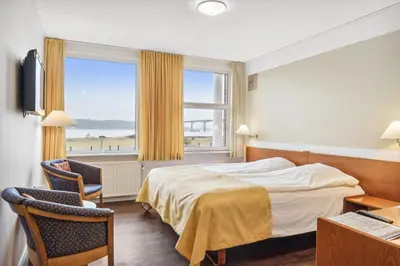a hotel room with a bed and a large window at Hotel Pinenhus in Glyngøre