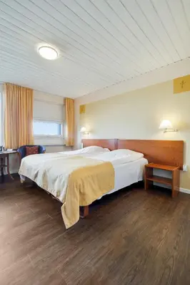 a bedroom with a large white bed in a room at Hotel Pinenhus in Glyngøre