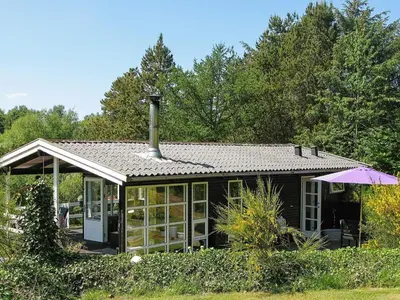 a small black house with a roof and an umbrella at 4 person holiday home in Højslev in Højslev