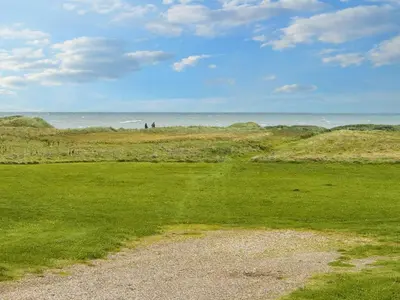 a field of grass with the ocean in the background at 5 person holiday home in Lemvig-By Traum in Trans