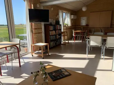 a living room with a tv and a table and chairs at Danhostel Fjaltring in Fjaltring