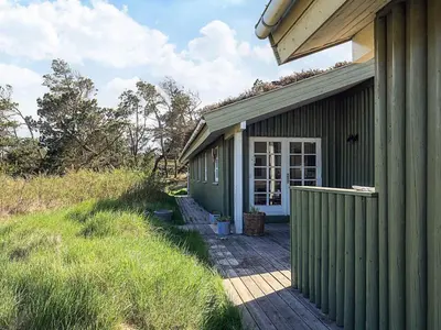 a green building with a porch and a door at 6 person holiday home in Løkken-By Traum in Løkken