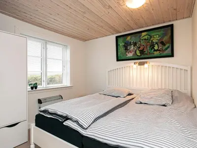 a bedroom with a bed with a painting on the wall at 6 person holiday home in Lemvig in Ferring