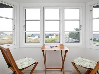 a table and two chairs in a room with windows at 6 person holiday home in Lemvig in Ferring