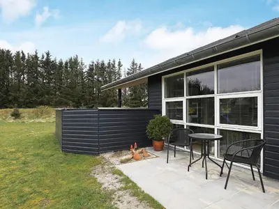 a black house with a table and chairs on a patio at Modern Retreat with Spa - By Traum Ferienwohnungen in Løkken
