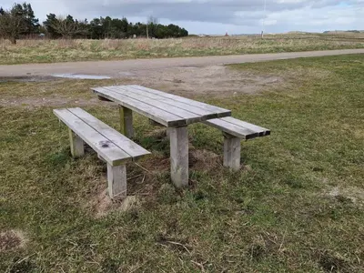 a wooden bench sitting in the grass next to a road at 8 person holiday home in Højslev-By Traum in Højslev