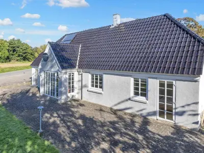 a white house with a black roof on a street at 10 person holiday home in Fur-By Traum in Fur