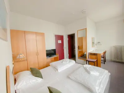 a bedroom with two white beds and a table at Løgstør Badehotel - Hotel du Nord in Løgstør