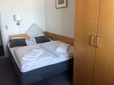 a bed with white sheets and green pillows on it at Løgstør Badehotel - Hotel du Nord in Løgstør