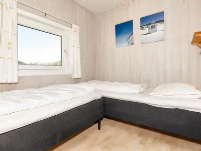 two beds in a room with a window at 10 person holiday home in Løkken in Løkken