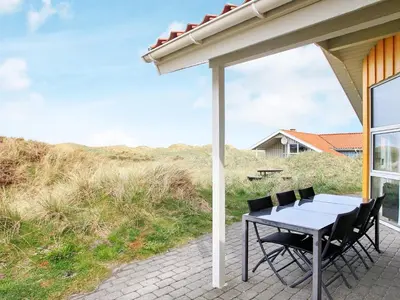 a table and chairs under an umbrella on a patio at 10 person holiday home in Løkken in Løkken