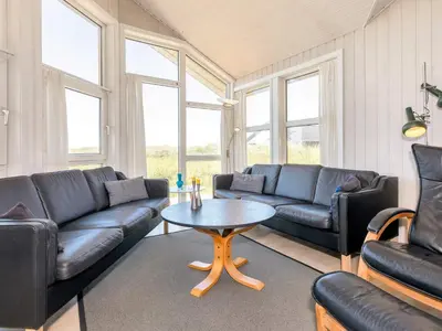a living room with black leather couches and a table at 10 person holiday home in Løkken in Løkken