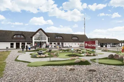 a building with a golf course in front of it at First Camp Klim Strand - Nordvestkysten in Fjerritslev
