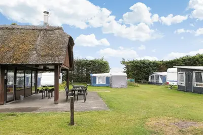 a building with a table and chairs and tents at First Camp Klim Strand - Nordvestkysten in Fjerritslev