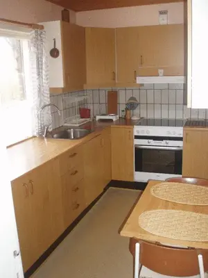 a kitchen with wooden cabinets and a sink and a table at Glyngøre Bed & Breakfast II in Glyngøre