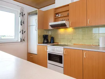 a kitchen with wooden cabinets and a white stove top oven at 10 person holiday home in Harboøre-By Traum in Harboør