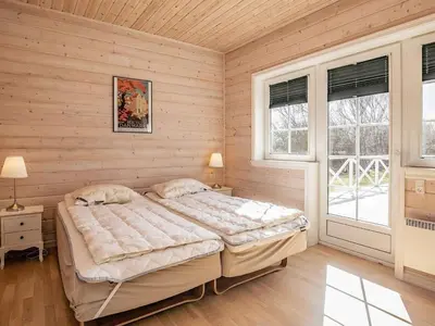 a bedroom with a large bed and two windows at Modern Retreat at Knud Strand - By Traum Ferienwohnungen in Spottrup
