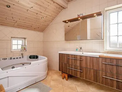 a bathroom with a tub and a sink and a mirror at Modern Retreat at Knud Strand - By Traum Ferienwohnungen in Spottrup