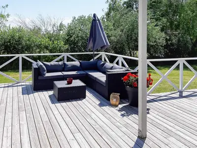 a couch sitting on a deck with an umbrella at Modern Retreat at Knud Strand - By Traum Ferienwohnungen in Spottrup