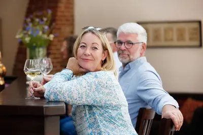 a woman sitting at a table with a glass of wine at Hotel Thinggaard in Hurup