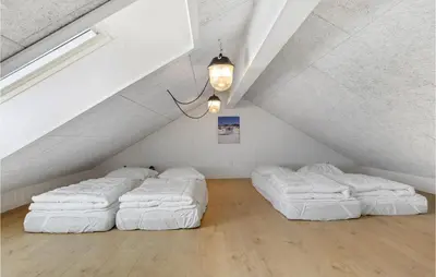 a attic room with three white beds in it at Lovely Home In Blokhus With Sauna in Blokhus